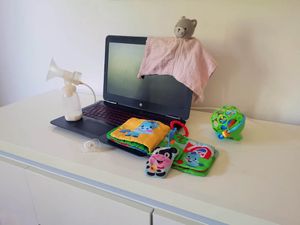 Ordinateur portable entouré de jouets et d'un biberon symbolisant la reprise du travail d'une maman à Brétigny-sur-Orge