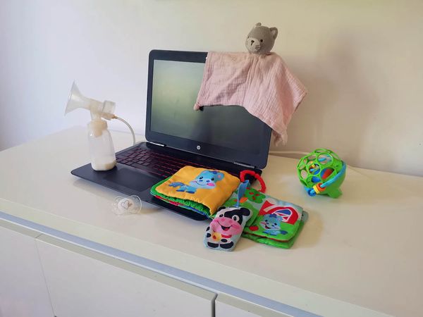 Ordinateur portable entouré de jouets et d'un biberon symbolisant la reprise du travail d'une maman à Brétigny-sur-Orge
